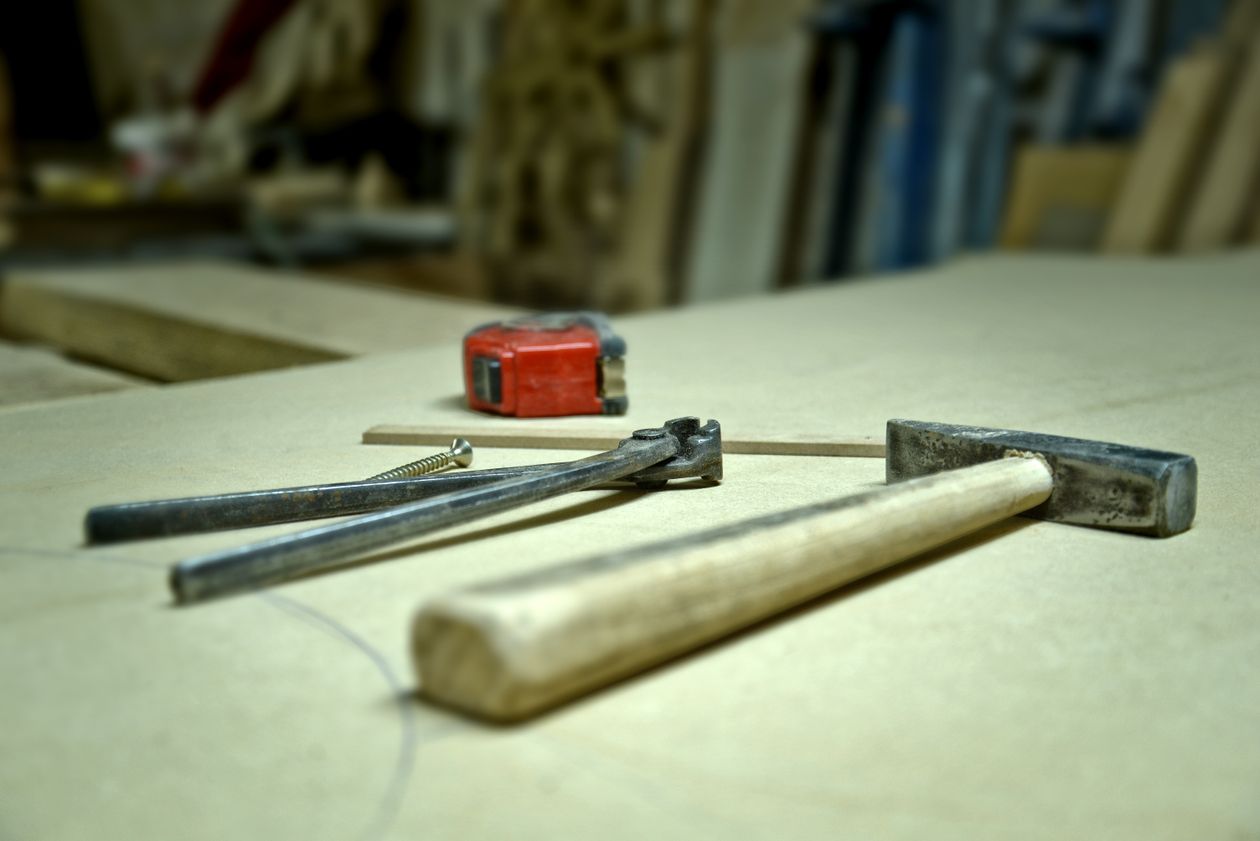 Real hammer, pincers, screw and tape measure arranged on a workshop bench