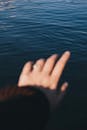 焦点不集中的手，戒指伸到荡漾的水面上