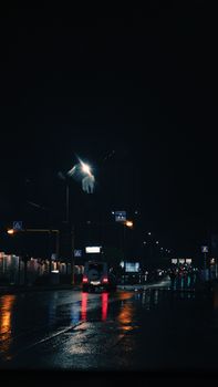 Urban street scene at night with rain and traffic lights reflecting on wet roads.