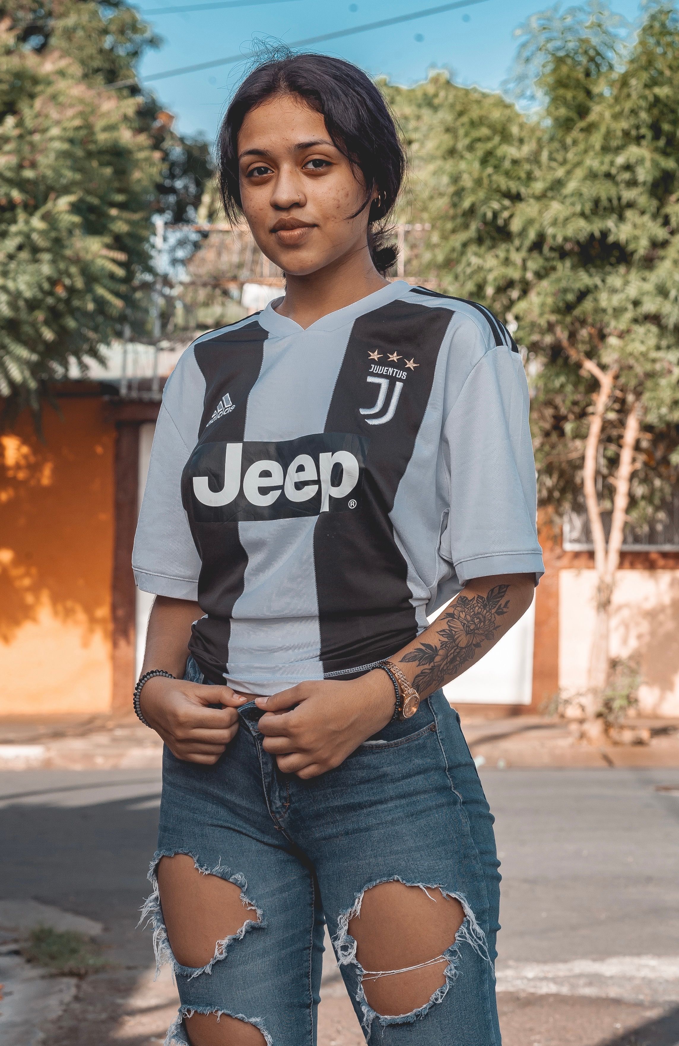 Woman in casual wear with tattoos and ripped jeans, outdoors in Managua.