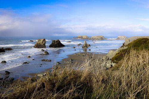 Free Dramatic coastal scenery with rocky shorelines and waves under a bright blue sky. Stock Photo