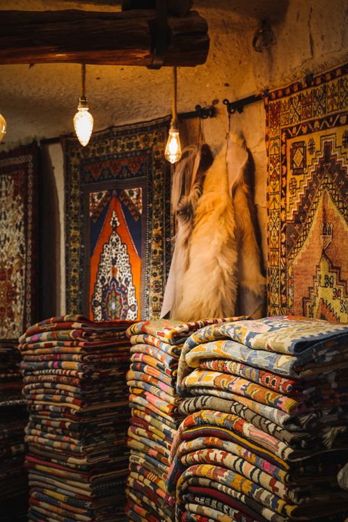 Free A cozy indoor scene showcasing stacked traditional Turkish carpets with warm lighting. Stock Photo
