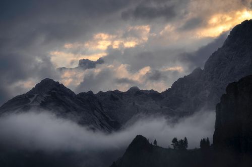 Free Misty Dolomite mountains in Cortina d'Ampezzo, captured at sunrise with dramatic clouds. Stock Photo