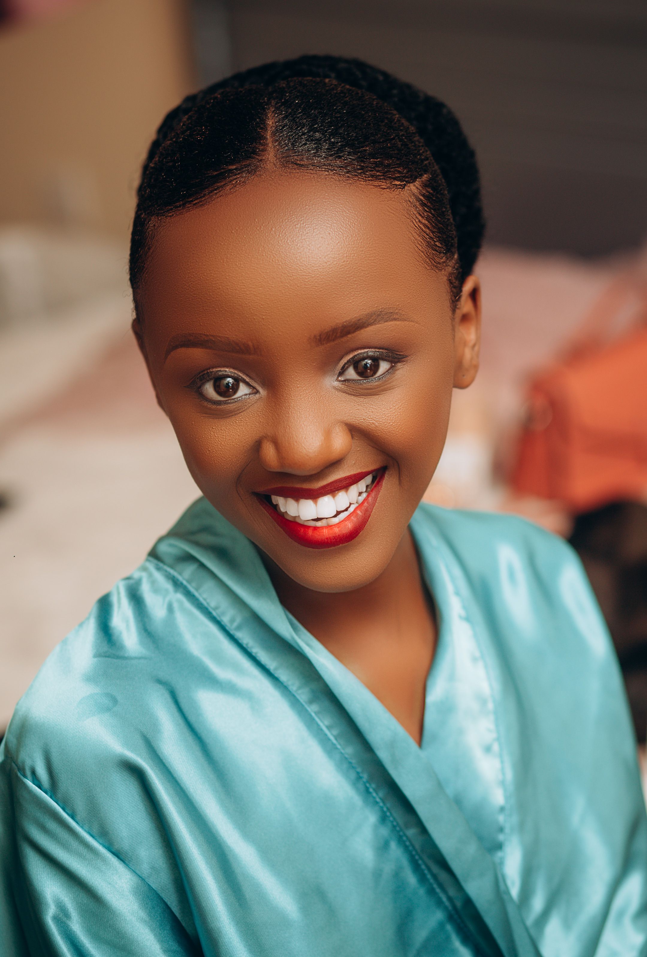 Close-up portrait of a smiling woman in a blue robe with vibrant makeup.