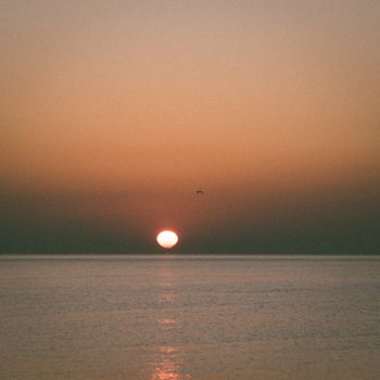 Serene ocean sunset with calm water and a vibrant sky, ideal for peaceful imagery.