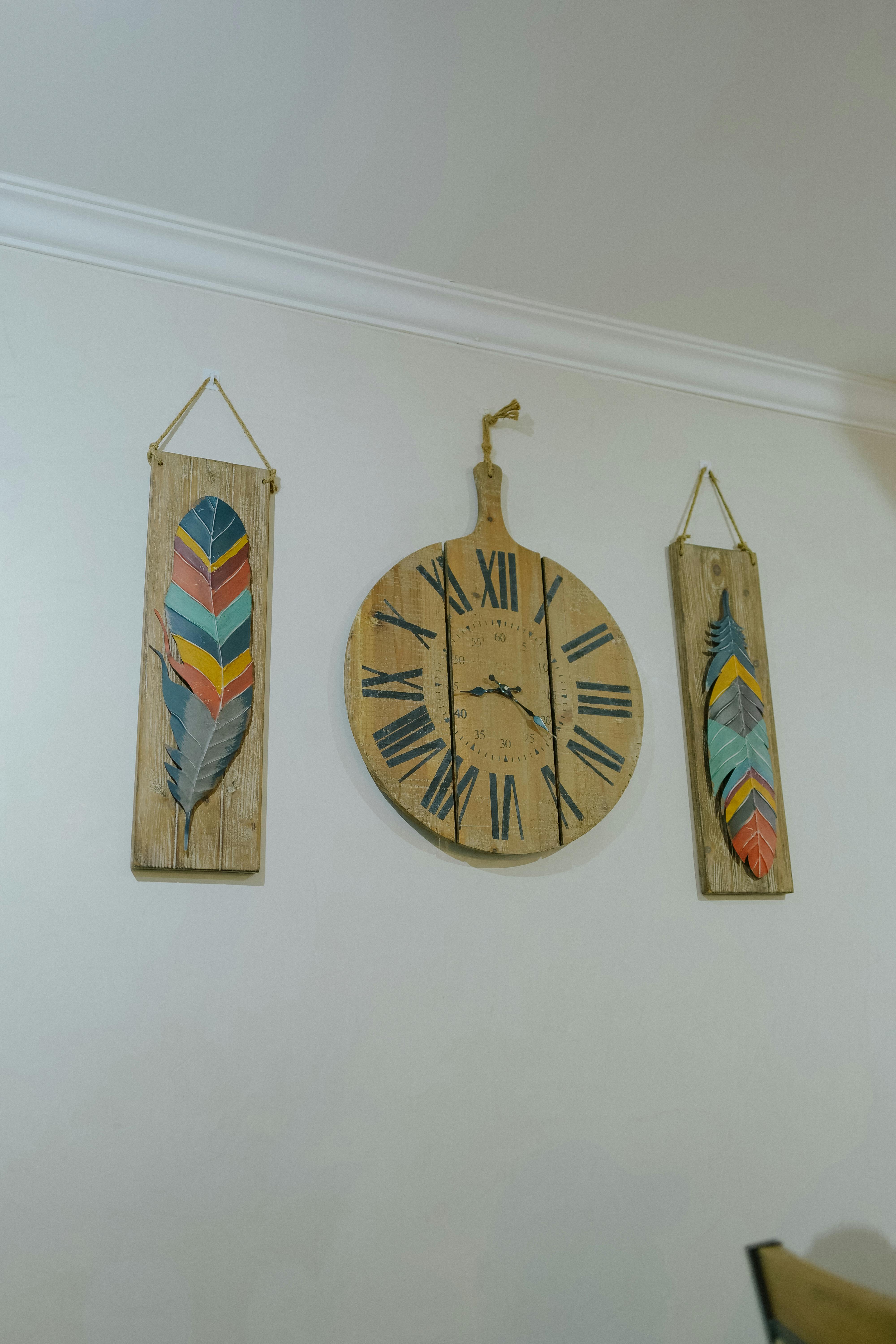 Wall featuring rustic clock and colorful feather decorations, perfect for a cozy home atmosphere.