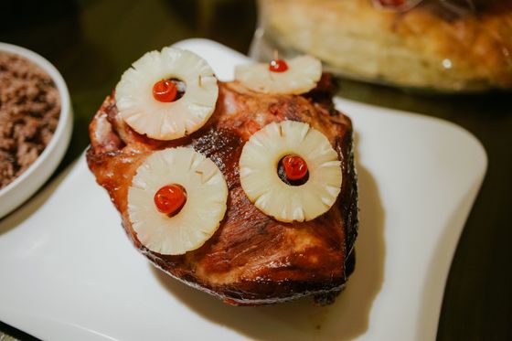 Baked glazed ham studded with pineapple rings and red cherries on a white plate