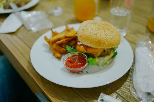 Free Tasty cheeseburger with crispy potato wedges and ketchup on a white plate. Stock Photo