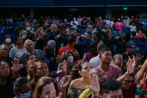 Free A diverse group of people attending an indoor event, raising hands in participation. Stock Photo
