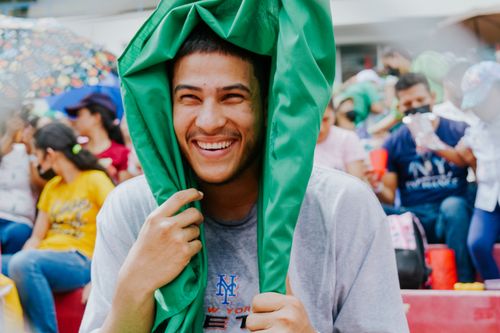 Free A cheerful man enjoys an outdoor event, laughing and covered with a green cloth. Stock Photo