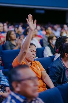 Woman in audience raising her hand during a public gathering, showing engagement. - Fotografer Sidoarjo