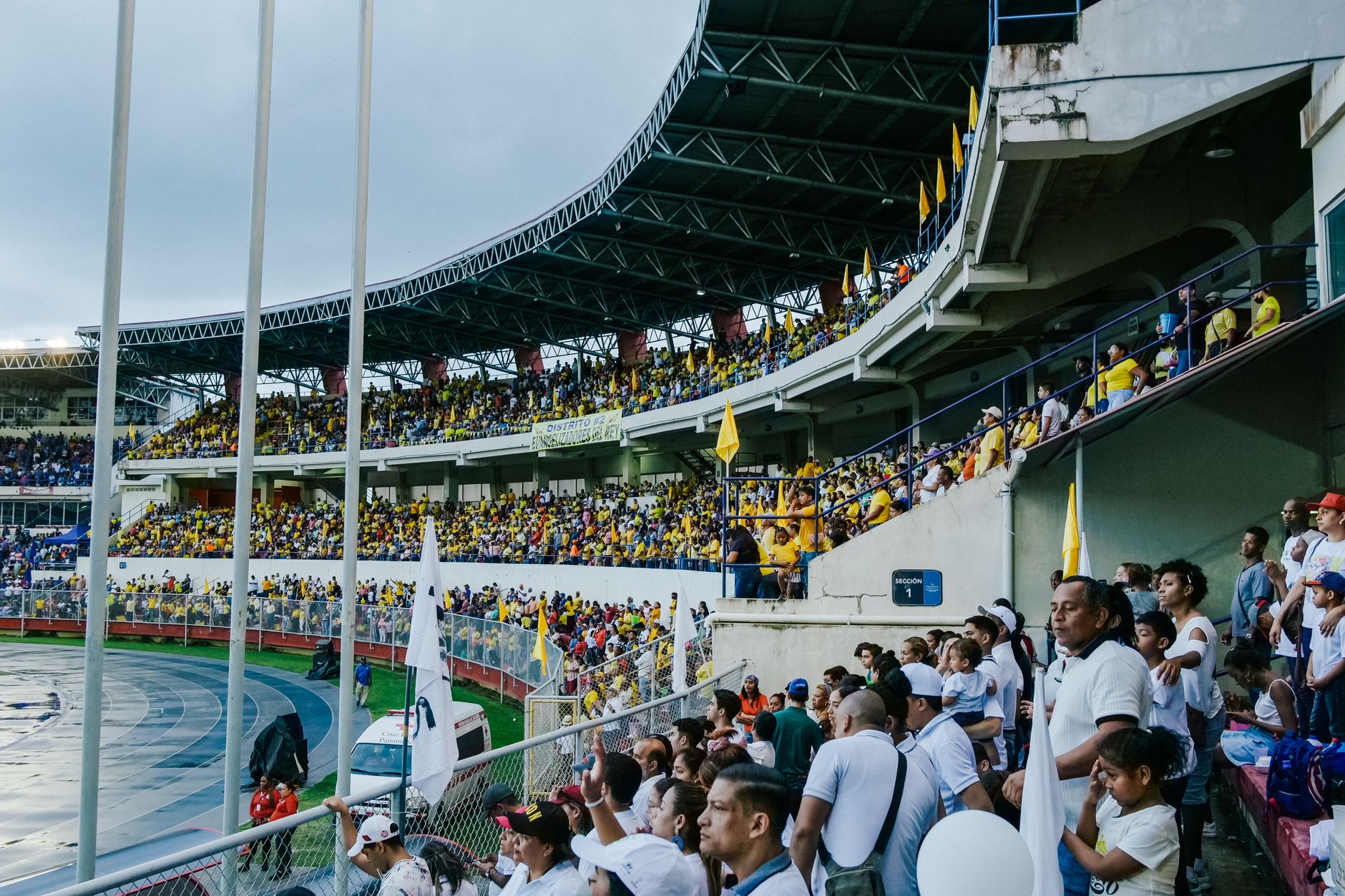 Energetic fans fill a stadium, creating an exciting sports atmosphere on an overcast day.