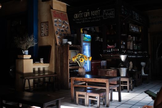 Charming vintage cafe interior featuring rustic decor, wooden furniture, and a vase of sunflowers.