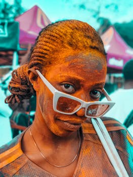 A woman with painted face at a lively festival, showcasing cultural vibrance and joy.