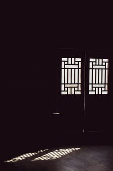Abstract view of sunlight casting geometric patterns through doors, creating a dramatic interior scene.