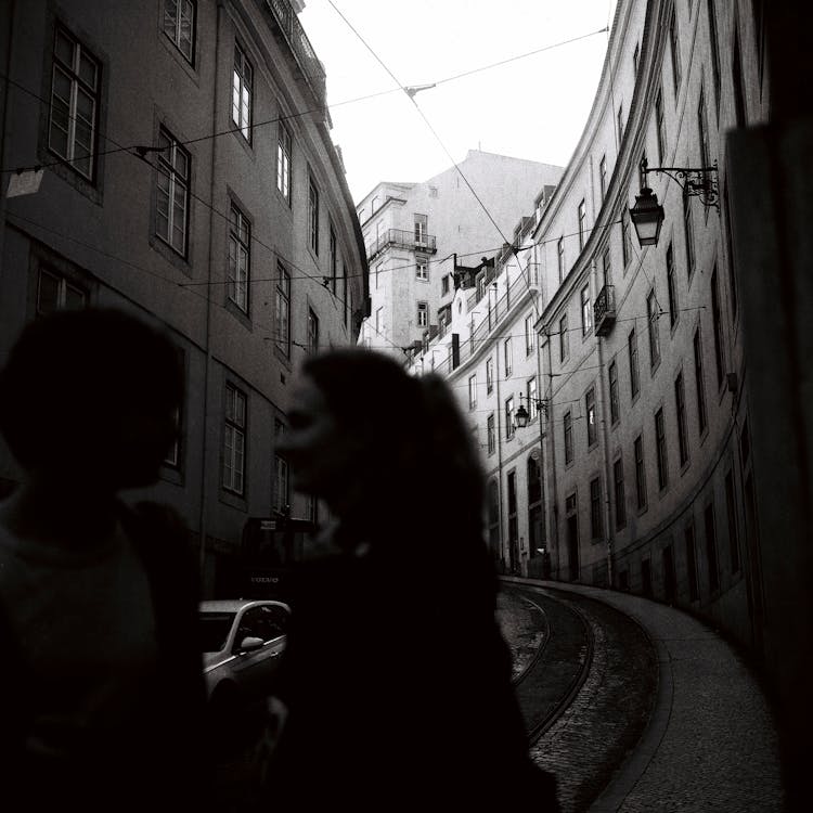 Woman Crossing A Street Between Buildings