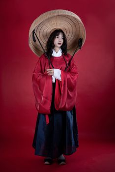 A striking image of a woman in traditional clothing with red and black tones, standing against a red background.