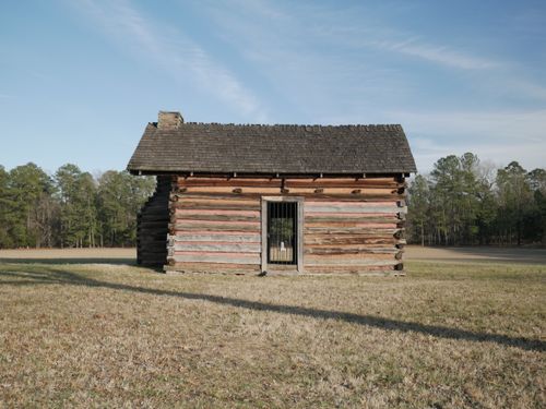 Free A solitary wooden shed stands on a field under a clear blue sky in Chickamauga, Georgia. Stock Photo