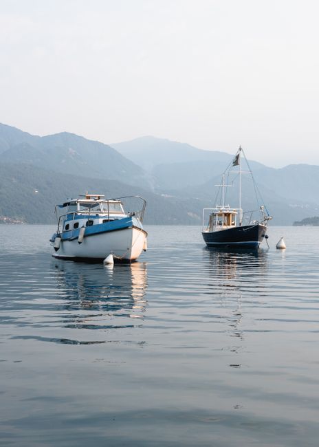 Two boats anchored on a peaceful lake with mountains in the background, perfect for travel inspiration.