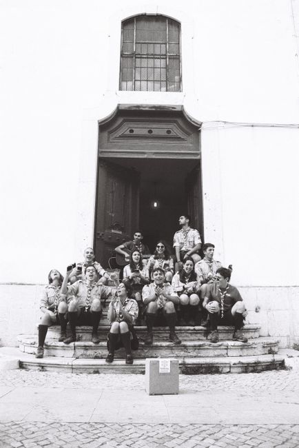 A black and white photo of young adults in scout uniforms sitting on steps in Lisbon, Portugal.