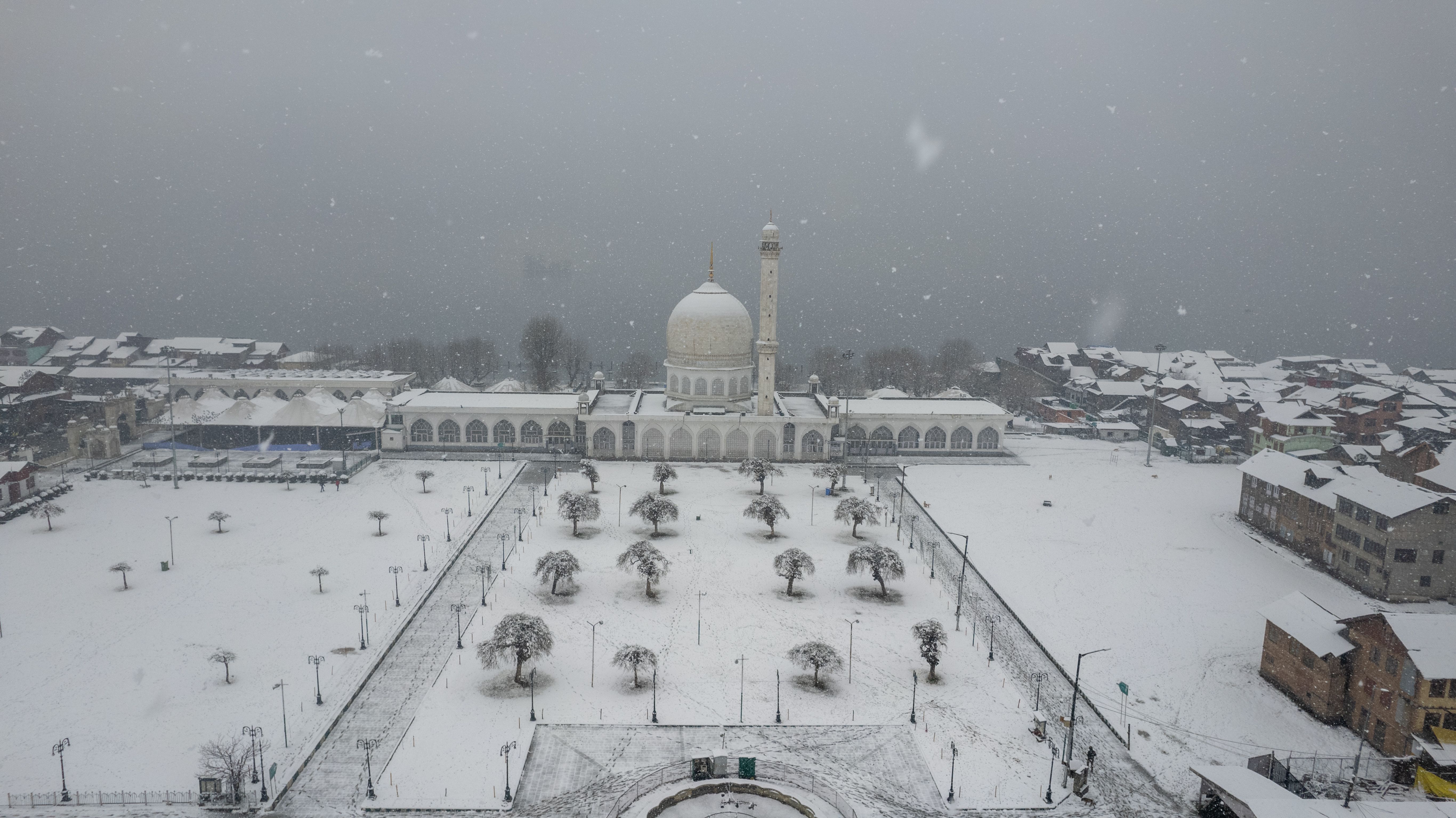 Aerial view of Hazratbal Shrine in winter snow, showcasing serene landscape in Srinagar, India.