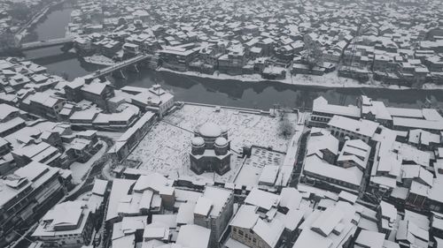 Free Snow blankets the historic buildings of Srinagar, showcasing its unique winter charm from above. Stock Photo