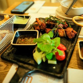 Close-up of a delicious Asian meal with fresh vegetables and dipping sauce on a tray.