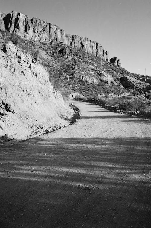 Grayscale Photo of Dirt Road on the Mountains