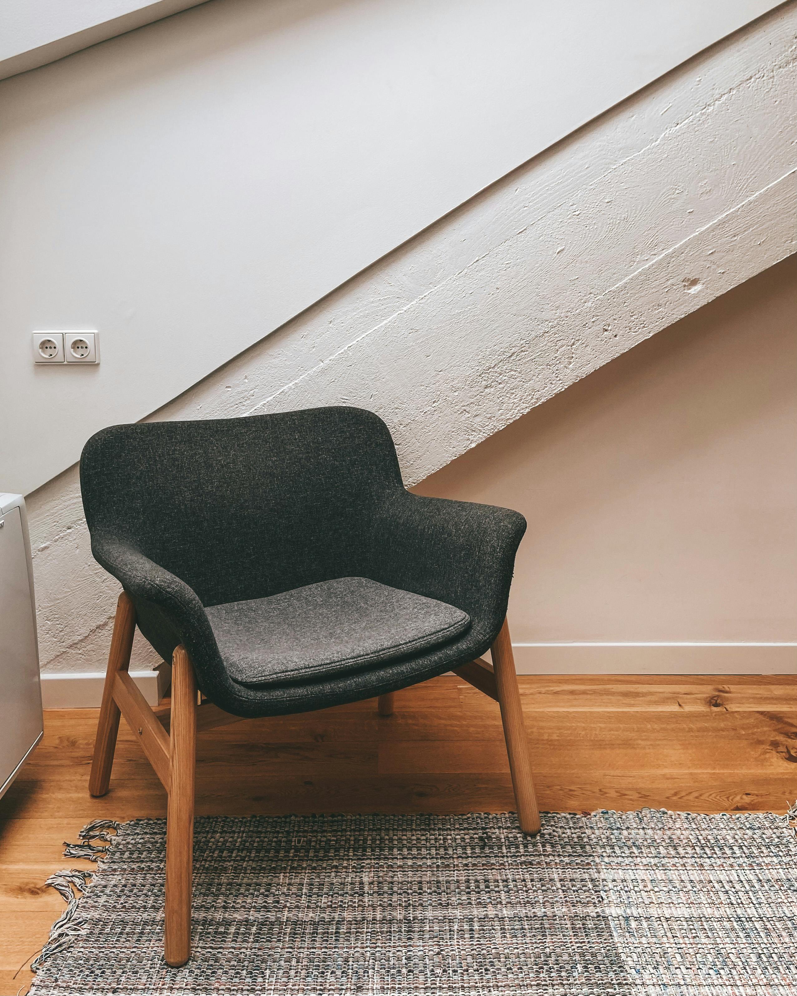 Free Stylish gray armchair in a contemporary attic with sloping ceilings and a cozy rug. Stock Photo