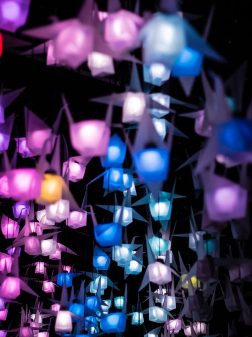 Free Colorful origami lanterns illuminated at night creating a festive and vibrant atmosphere. Stock Photo