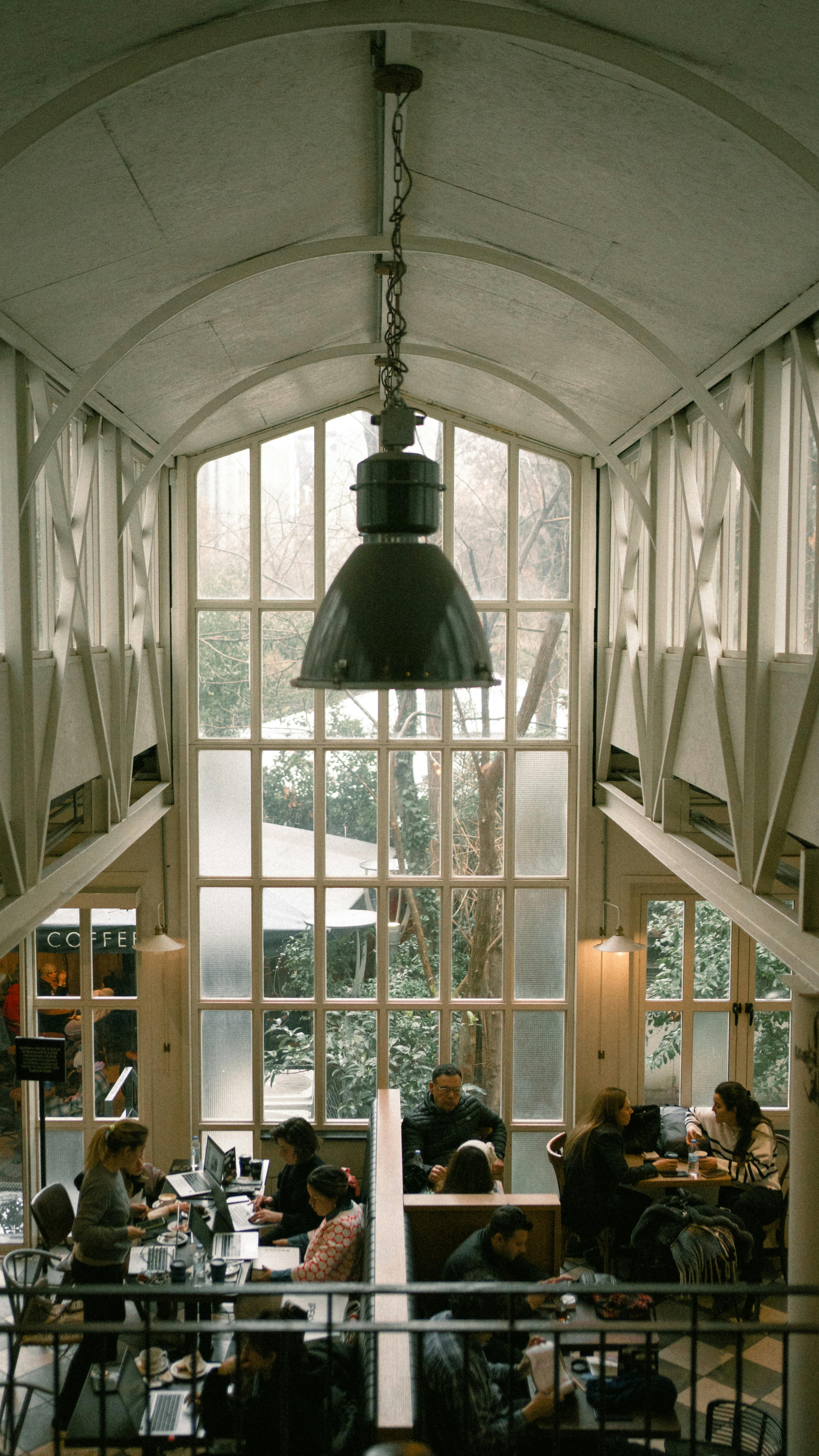 Café interior in İstanbul with people enjoying a cozy atmosphere. Modern design and tall windows.