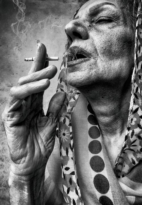 Free Black and white portrait of an elderly woman smoking a cigarette, conveying depth and emotion. Stock Photo