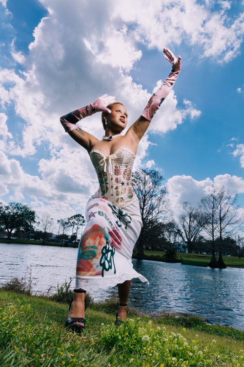 Free Stylish woman in corset and gloves posing by a lake in Orlando with a dramatic sky. Stock Photo