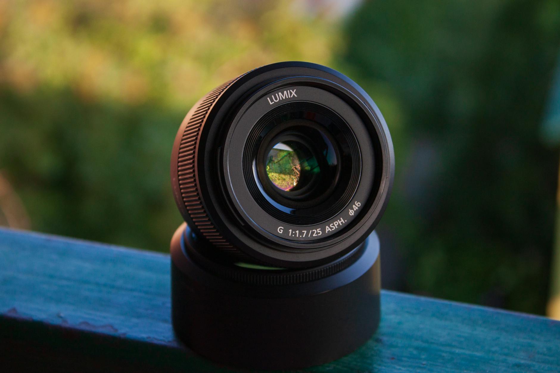 Detailed photo of a Lumix camera lens with blurred green background, showcasing optical technology.
