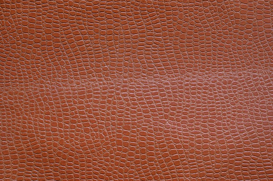 Close-up of a textured brown leather surface resembling reptile skin, highlighting intricate patterns.