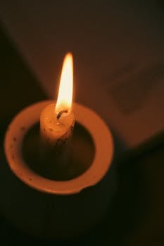 Close-up of a lit candle in a dark room for ambiance.