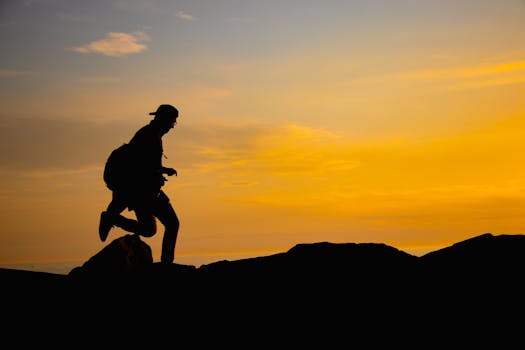 Silhouette of a person hiking on a mountain with a breathtaking sunrise sky background.
