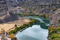 秋天，一条宁静的河流蜿蜒穿过岩石峡谷，展现出树叶生机勃勃的壮丽景色