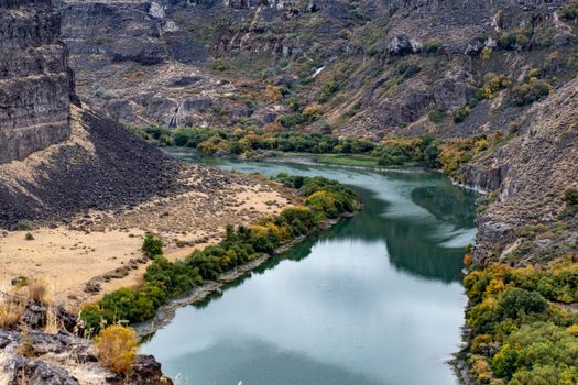 秋天，一条宁静的河流蜿蜒穿过岩石峡谷，展现出树叶生机勃勃的壮丽景色