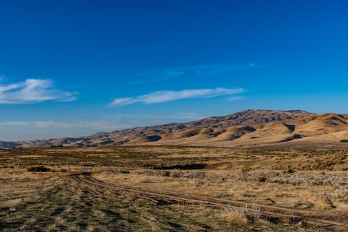 Free Serene desert landscape with rolling hills under a bright blue sky, showcasing nature's arid beauty. Stock Photo