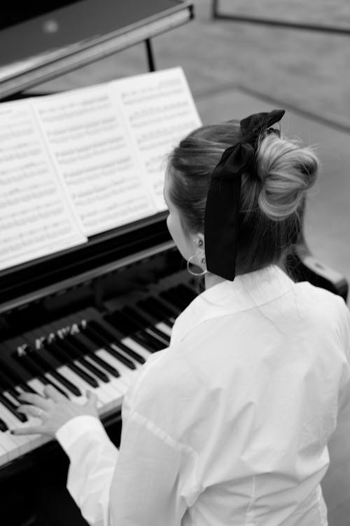 Grayscale Photo of a Woman Playing the Piano 