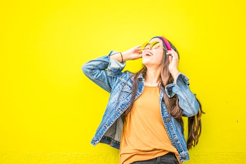 Free Smiling Woman Looking Upright Standing Against Yellow Wall Stock Photo