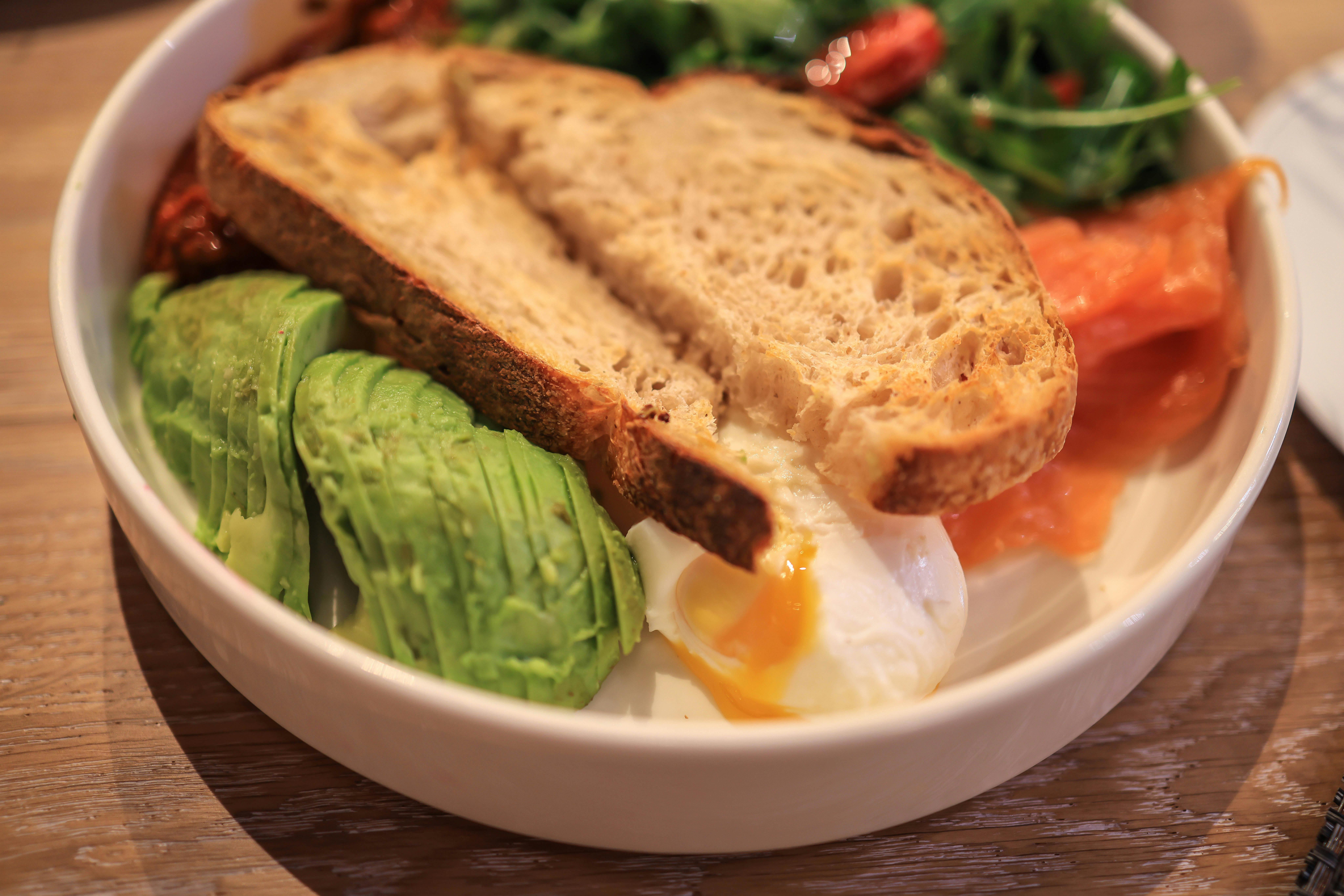 Delicious brunch dish featuring avocado, poached egg, and toast in a clean, minimalist setting.