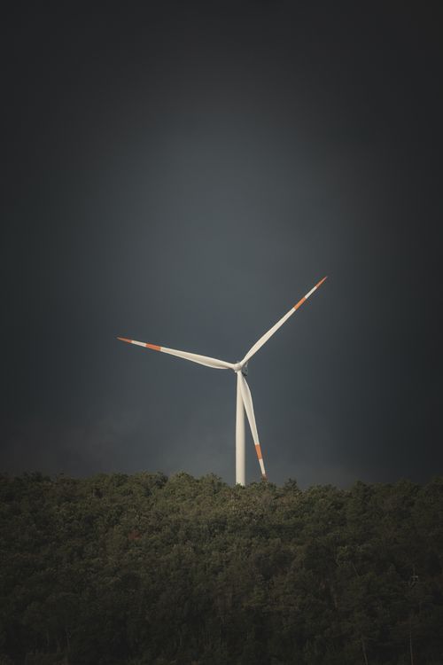 Free A solitary wind turbine stands tall against a dark, moody sky, symbolizing renewable energy. Stock Photo