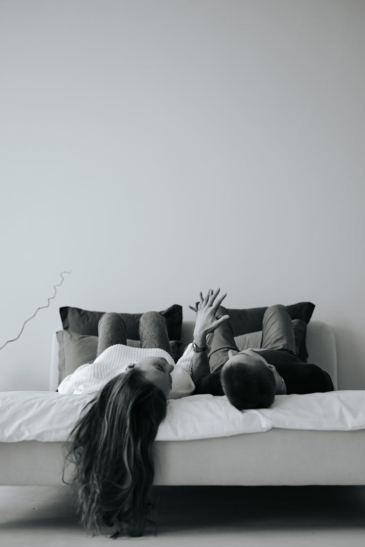 Couple Lying In Bed Holding Hands