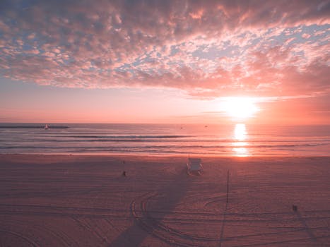 Beautiful sunrise over a serene Los Angeles beach with a lifeguard tower and vast ocean horizon.