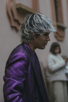 Stylish person with blonde hair in a purple jacket, captured in Milan's vibrant street scene.