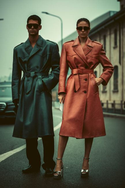 Fashion-forward models posing in coats on a city street, exuding modern style.