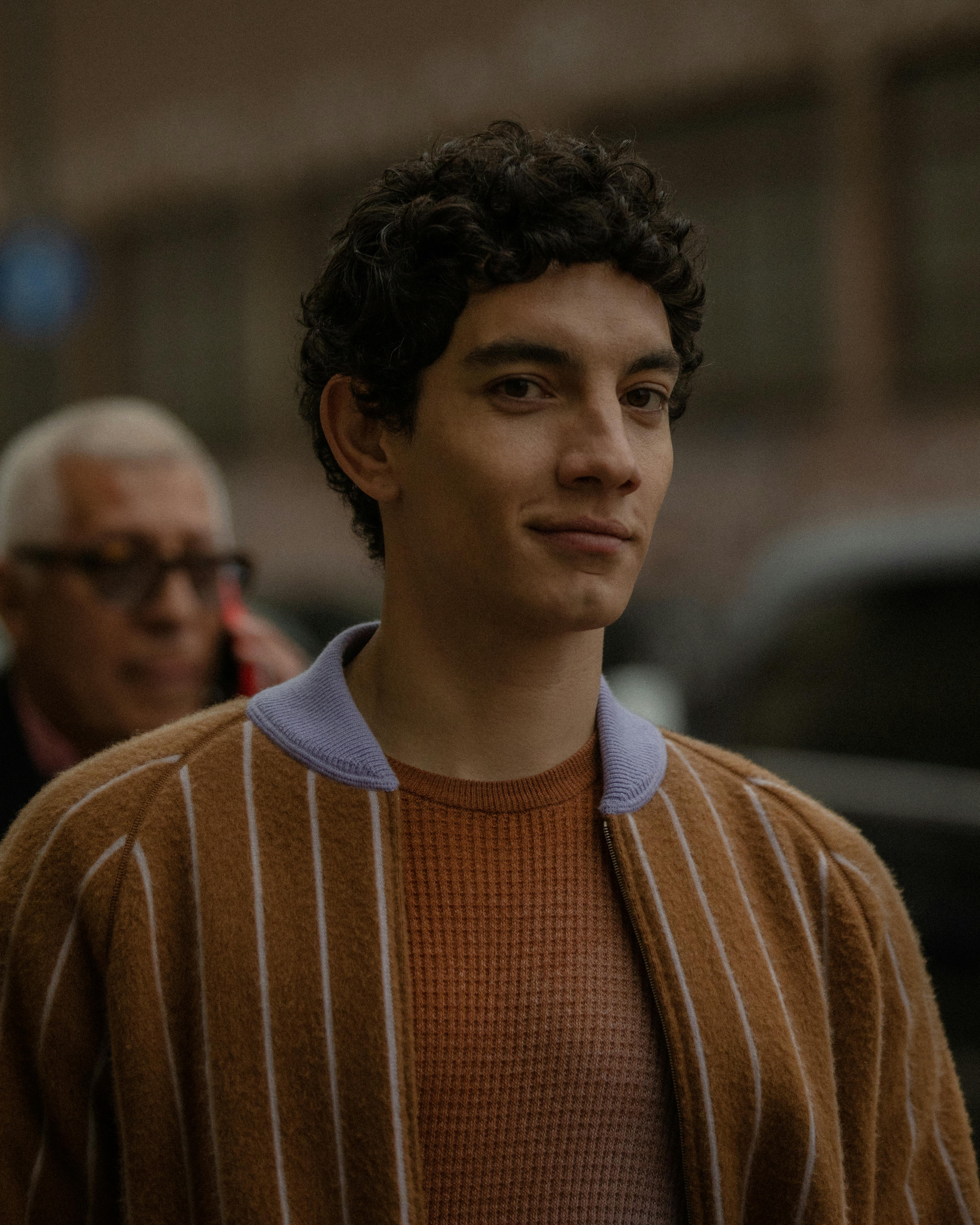 Portrait of a stylish young man smiling outdoors in an urban setting. Captured during daytime.