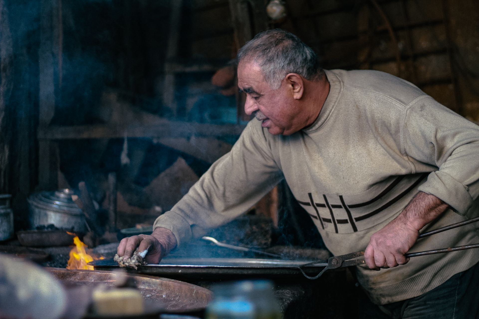 Senior craftsman works with fire in a traditional workshop in Denizli, Türkiye.
